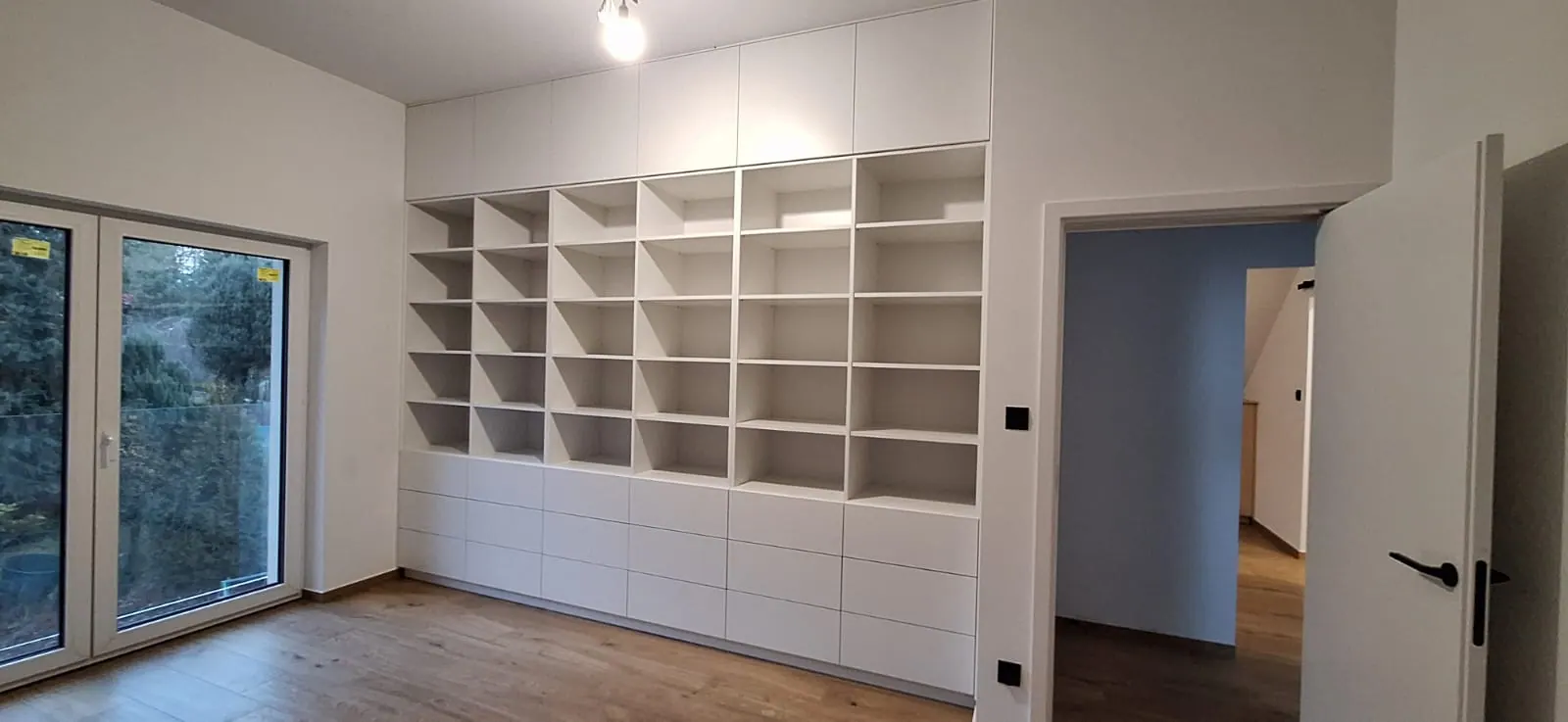 Biała biblioteka zajmująca całą ścianę